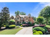 Stunning brick and stone home with manicured landscaping and a circular driveway at 8340 Colonial Pl, Duluth, GA 30097