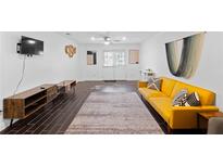 Spacious living room featuring dark wood flooring and a bright yellow sofa at 405 Branch Forest Way, Stockbridge, GA 30281