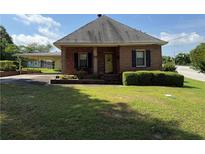 Charming single-story brick home with a manicured lawn, mature landscaping, and covered carport at 871 Malcom Se St, Conyers, GA 30012