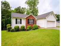 Charming single-story home with red brick accents, white siding, well-maintained landscaping, and attached garage at 1444 Elliotts Lane, Auburn, GA 30011