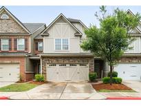 Charming townhome featuring a stone and neutral siding exterior, a two-car garage, and manicured landscaping at 1630 Marsanne Nw Ter # 27, Kennesaw, GA 30152