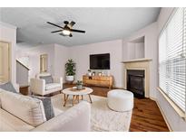 Bright living room with modern ceiling fan, fireplace, and plush white furniture at 867 Crested Hawk Trl, Sugar Hill, GA 30518
