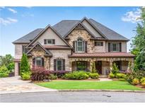 Stunning brick and stone home featuring meticulous landscaping and charming architectural details at 212 Fernwood Pl, Woodstock, GA 30188