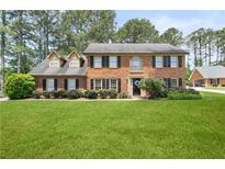 Traditional brick home with manicured lawn and mature trees in a well-maintained community at 3472 Honeycomb Se Dr, Conyers, GA 30094