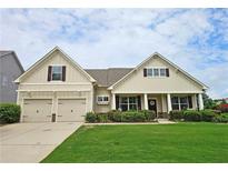 Charming, light beige home featuring a two-car garage, manicured lawn, and colorful flowerbeds at 4024 Broadmoor Sw Ct, Austell, GA 30106