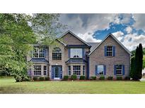 Elegant brick home featuring a lush lawn, beautiful windows and blue shutters at 4706 Derby Loop, Fairburn, GA 30213