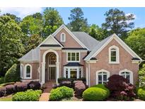 Stately brick home featuring manicured landscaping, arched windows, and a welcoming entrance at 1200 Bay Pointe Terr Ter, Alpharetta, GA 30005
