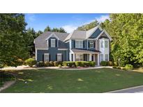 Charming two-story home with blue siding, stone accents, manicured lawn, and mature trees at 1210 Magnolia Park Cir, Cumming, GA 30040