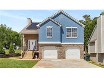Charming two-story home featuring a brick facade, blue siding, and a two-car garage at 966 Crest Ridge Sw Dr, Marietta, GA 30060