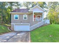 Charming home featuring an attached garage and inviting front porch with white railing at 4831 Oak Path, Stone Mountain, GA 30088