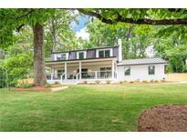 Charming white brick home with a metal roof and a welcoming front porch surrounded by a lush green lawn at 550 Stewart Nw Ave, Marietta, GA 30064