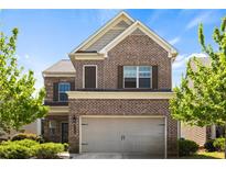 Two-story brick home featuring an attached two-car garage, manicured shrubbery, and a gable-accented roofline at 1749 Charcoal Ives Rd, Lawrenceville, GA 30045