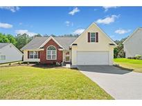 Charming home featuring a well-manicured lawn, brick accents, and a two-car garage with a lovely blue sky overhead at 1835 Patrick Mill, Buford, GA 30518