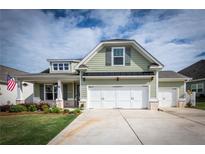 Charming home with green siding, white garage doors, and a well-manicured lawn on a sunny day at 98 Heritage Pointe Dr, Villa Rica, GA 30180