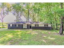 Charming home with a dark brick facade, contrasting white siding, and a lush green lawn at 545 Fayetteville Rd, Fairburn, GA 30213