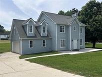 Charming two-story home with light blue siding, gray roof, attached garage and expansive green lawn at 1201 Saint Andrews Dr, Auburn, GA 30011
