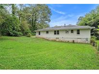 Spacious backyard features a well-maintained lawn and the home's exterior with painted white brick at 2406 Tilson Rd, Decatur, GA 30032