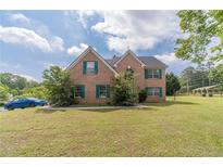A well-kept brick two story home has a manicured lawn and green shutters at 4023 Port Springs Trl, Snellville, GA 30039