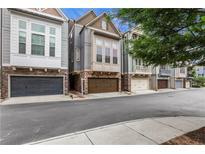 Charming townhomes featuring stone accents, gray siding, and attached two-car garages at 3005 Devoncroft Se St, Smyrna, GA 30080