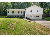 Charming two-story white home with a covered porch and a well-manicured lawn and driveway at 2035 Stilesboro Nw Dr, Kennesaw, GA 30152