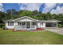 Charming single-story home featuring a covered porch and carport on a sunny day at 4067 Lenora Church Rd, Snellville, GA 30039