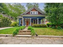 Charming blue home features a welcoming front porch, a wooden front door, and lush landscaping at 549 Atwood Sw St, Atlanta, GA 30310