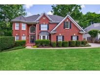 Charming two-story brick home featuring manicured lawn, mature trees, and traditional architectural details at 265 Dogwood Walk Ln, Norcross, GA 30071