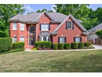 Charming two-story brick home featuring a well-manicured lawn and mature trees at 265 Dogwood Walk Ln, Norcross, GA 30071