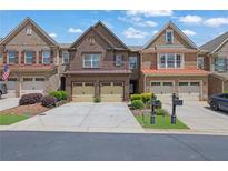 Brick townhome featuring an attached two-car garage, manicured landscaping, and a driveway perfect for multiple cars at 1929 Brightleaf Way, Marietta, GA 30060