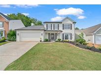 Charming two-story home with a well-manicured lawn, black shutters and a two car garage at 565 Barsham Way, Johns Creek, GA 30097
