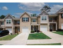 Townhome exterior with a manicured lawn, attached garages, and neutral paint colors, under a bright sky at 10162 Benton Woods Dr, Covington, GA 30014