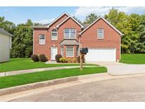 Charming two-story brick home with a well-manicured lawn and attached two-car garage at 1127 Oak Hollow Ct, Hampton, GA 30228
