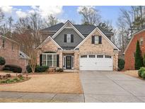 Charming brick two-story home with a well-manicured front yard and a two car garage at 1525 Camden Cove Dr, Cumming, GA 30040