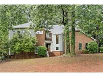 Charming two-story home with a brick and stucco facade and mature trees in a quiet, wooded lot at 175 River Run, Roswell, GA 30075
