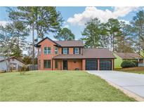 Charming brick home boasts mature trees, fresh lawn, and a three-car garage at 8914 Gardener Dr, Jonesboro, GA 30238