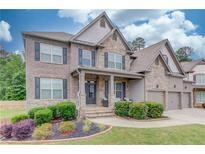 Charming two-story home boasts a stone and brick facade, a well-manicured lawn, and a welcoming front porch at 4240 Summer Breeze Way, Buford, GA 30518