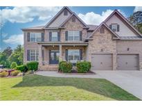 Charming two-story home showcasing a stone and brick facade, well-manicured lawn, and a welcoming front porch at 4240 Summer Breeze Way, Buford, GA 30518
