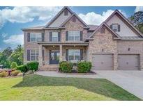 Charming two-story brick home featuring a three car garage and manicured front lawn at 4240 Summer Breeze Way, Buford, GA 30518