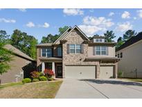 Inviting two-story home featuring a stone facade, attached two-car garage, and a well-manicured front yard at 6977 Demeter Dr, Atlanta, GA 30349