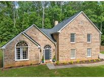 Traditional brick home with manicured lawn and beautiful architectural details in a wooded setting at 8035 Canter Ln, Alpharetta, GA 30009