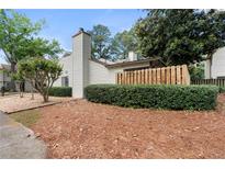 Cozy home featuring wood siding, a chimney, a neat hedge, and beautiful surrounding trees at 1104 Country Ct, Lawrenceville, GA 30044
