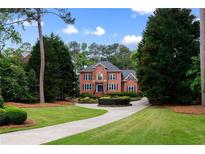 Stately brick home featuring a circular driveway, mature landscaping, and classic architectural details at 130 Robin Rd, Marietta, GA 30067