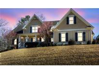 Charming two-story home featuring a welcoming front porch, gable roof, and manicured landscaping, set against a vibrant twilight sky at 103 Old Avery Dr, Canton, GA 30115
