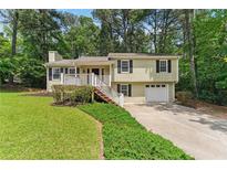 Charming split-level home with a well-maintained lawn and inviting front porch at 708 Wind Song Trce, Woodstock, GA 30189