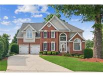 Inviting two-story brick home with a well-manicured lawn, two-car garage, and charming landscaping at 1316 Wind Chime Ct, Lawrenceville, GA 30045