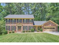 Charming brick two-story home with black shutters and a well-manicured lawn and lush landscaping at 3592 Midvale Cv, Tucker, GA 30084