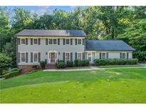Traditional two-story home featuring a well-maintained lawn and mature trees for added privacy at 5143 Meadowlake Ln, Dunwoody, GA 30338