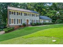 Charming two-story home with a well-manicured lawn and lush landscaping at 5143 Meadowlake Ln, Dunwoody, GA 30338
