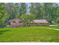 Charming brick and siding home with a well-manicured lawn and mature trees at 5401 Smoke Rise Dr, Smoke Rise, GA 30087