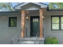 Inviting home entrance with freshly painted gray brick, black trim, wood accents and modern black railings at 1643 Flintwood Se Dr, Atlanta, GA 30316